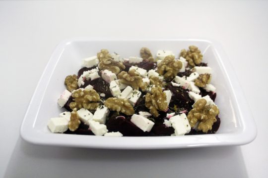 Ein Teller mit geschnittenen Roten Rüben, Käse und Walnüssen.