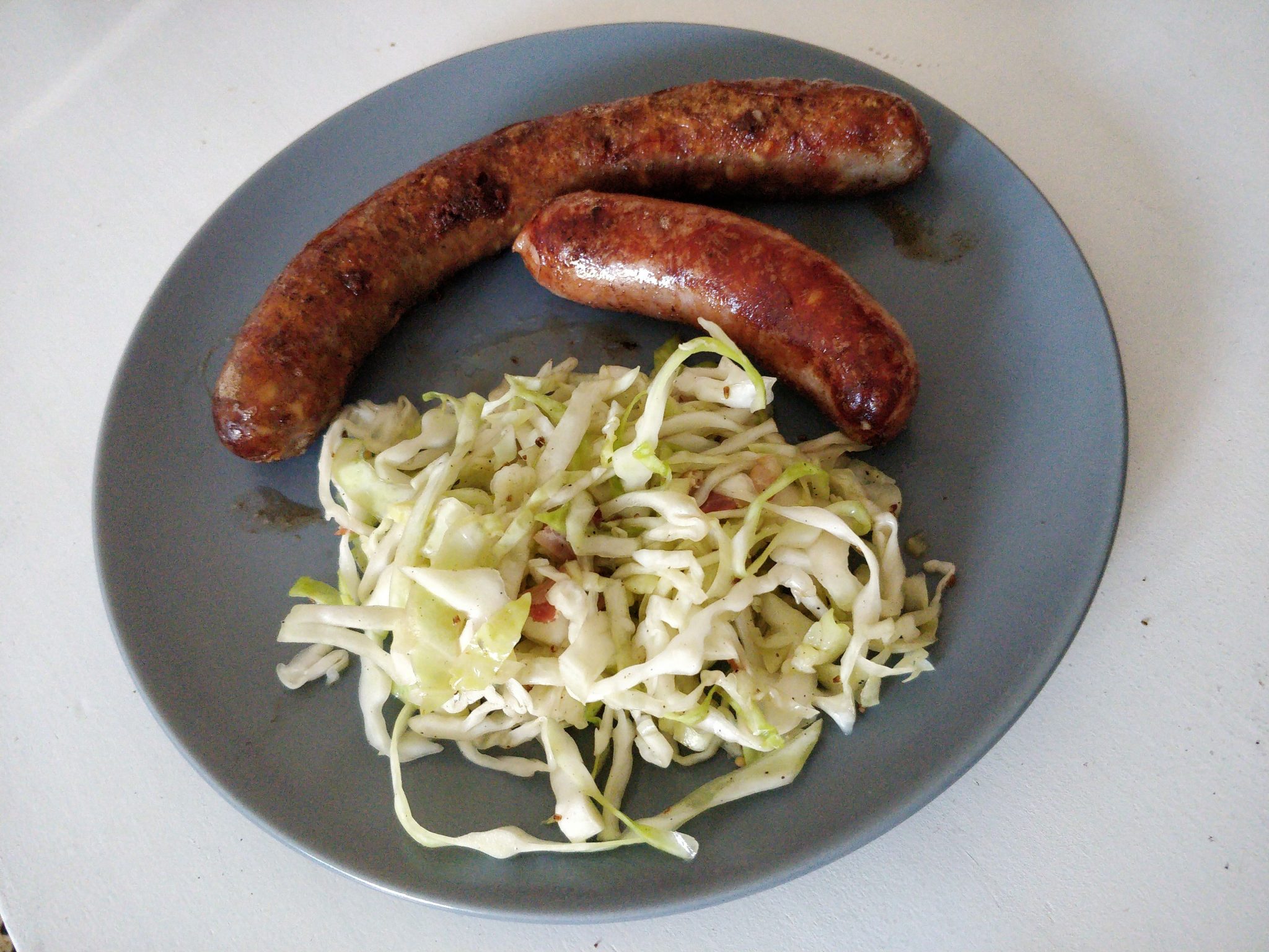 Zwei Käsekrainer auf einem Teller mit Krautsalat