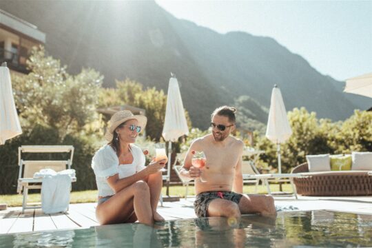Ein Paar genießt am Pool im Hotel theiner's garten Drinks.