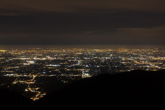 Zu sehen ist eine Stadt und all ihre Lichter bei Nacht.