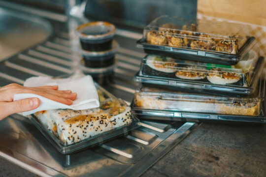 Man sieht Essen in gestapelten Plastikbehältern vom Lieferservice.