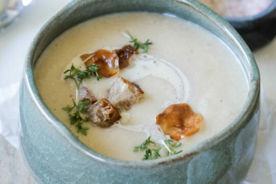Man sieht eine Schüssel cremiger Suppe mit Croûtons.