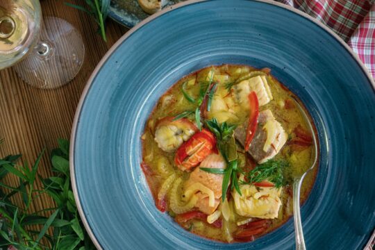 Zu sehen ist eine Fischsuppe in einem blauen Teller von oben.