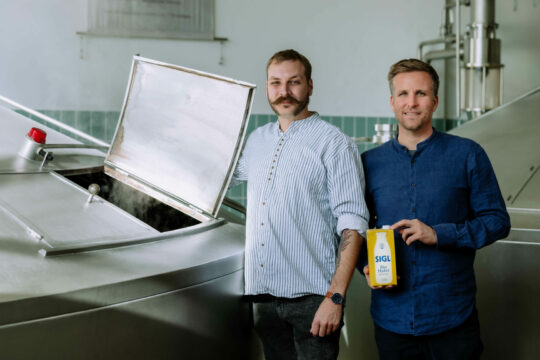 Man sieht zwei Menschen in einer industriellen Küche.