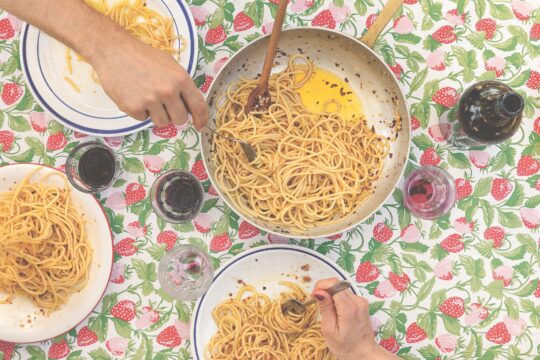 Ein Esstisch mit Pasta in einer Schüssel und auf Tellern.