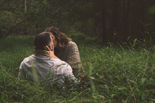 Zwei Personen die sich in einem Feld küssen.
