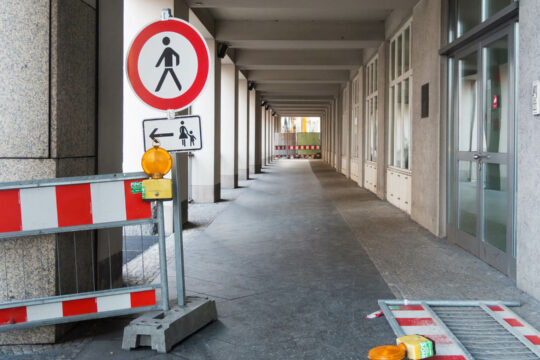 Ein Hauseingang an dem einige Absperrungsgitter zu sehen sind.