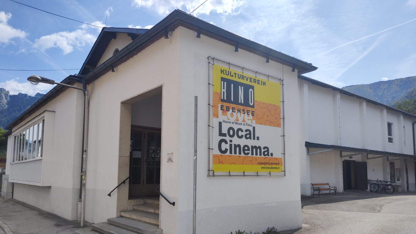 Ein schlichtes Gebäude auf dem ein Schild mit »Kultuverein Kino Ebensee. Local Cinema« zu sehen ist.