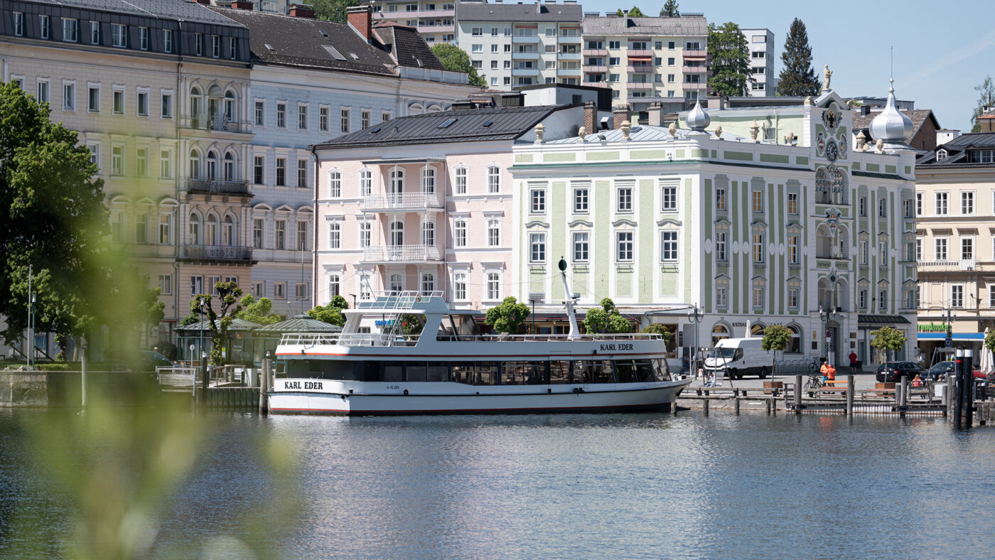 Ein Boot auf einem See vor gepflegten alten Gebäuden.