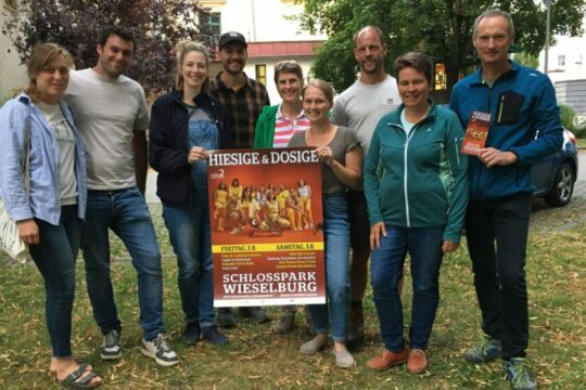 Mehrere Personen posieren mit einem Festivalplakat.