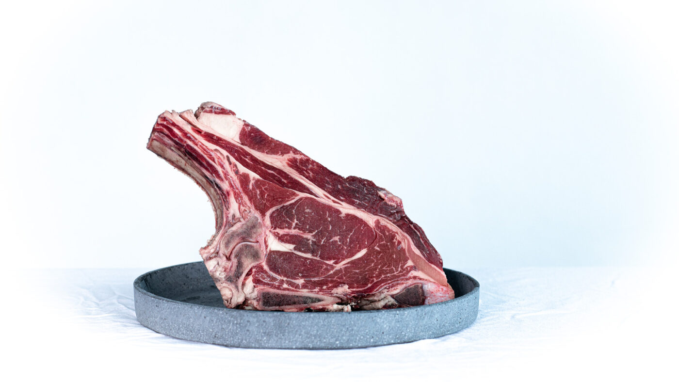 Ein Stück Fleisch am Knochen auf einem Teller.