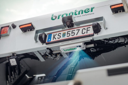 Ein KFZ von hinten unten, unter dem Nummernschild leuchtet Licht aus einer Box.