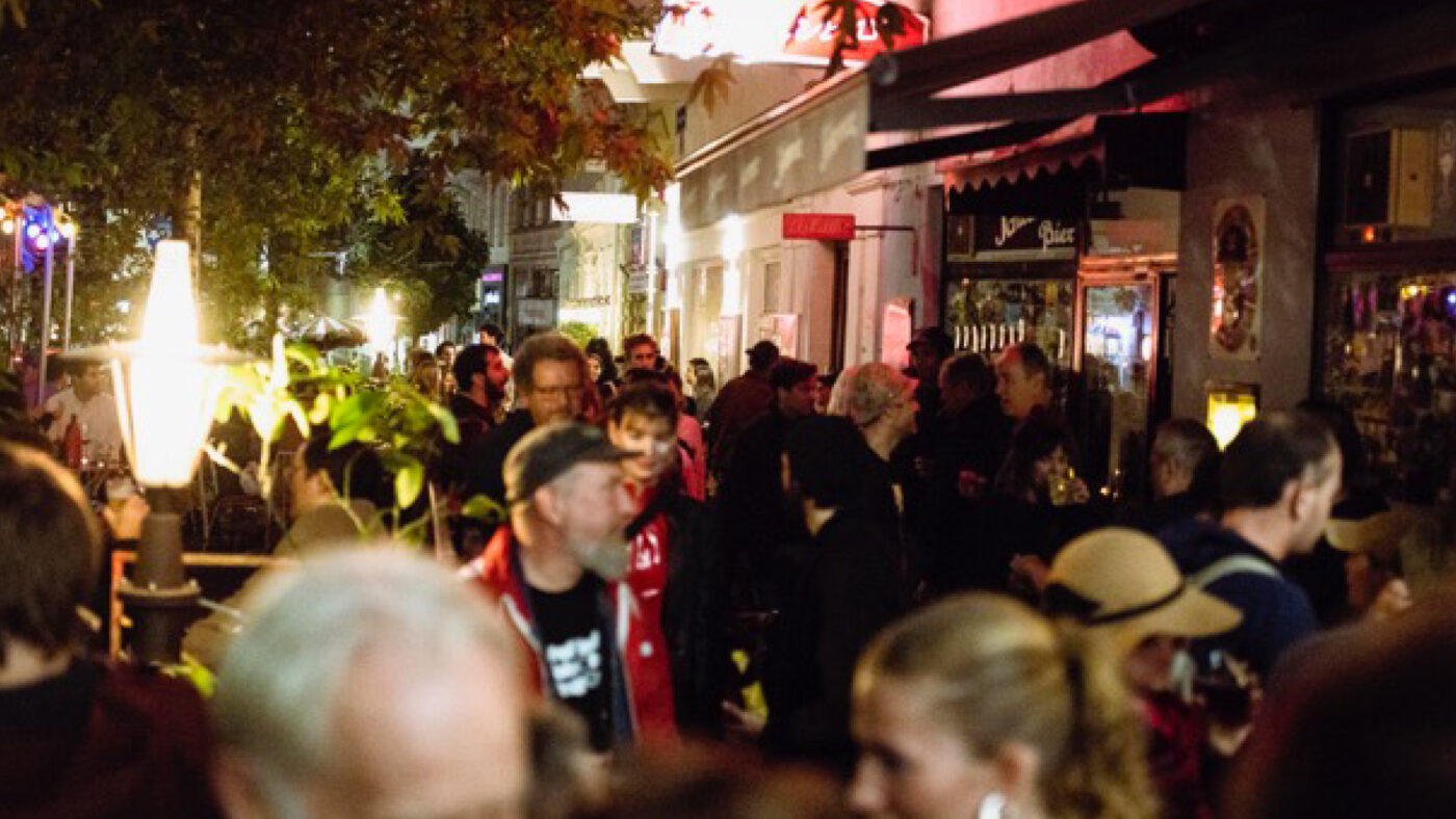 Eine Menschenmenge steht vor einem Lokal.