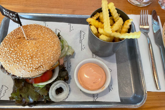 Ein Burger mit Pommes Frites und Sauce auf einem Tablett.