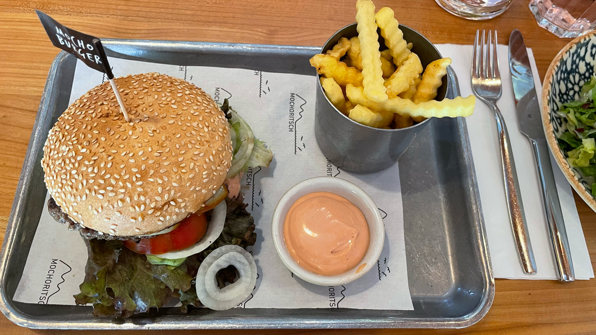 Ein Burger mit Pommes Frites und Sauce auf einem Tablett.