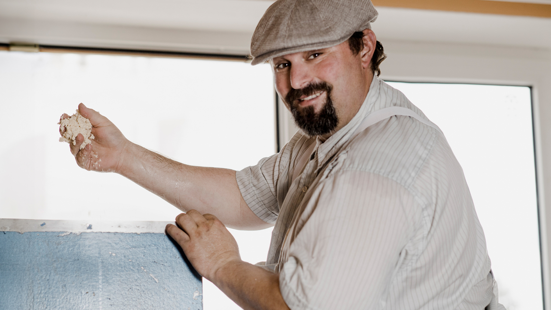 Eine Person arbeitet mit Teig und lächelt in die Kamera.