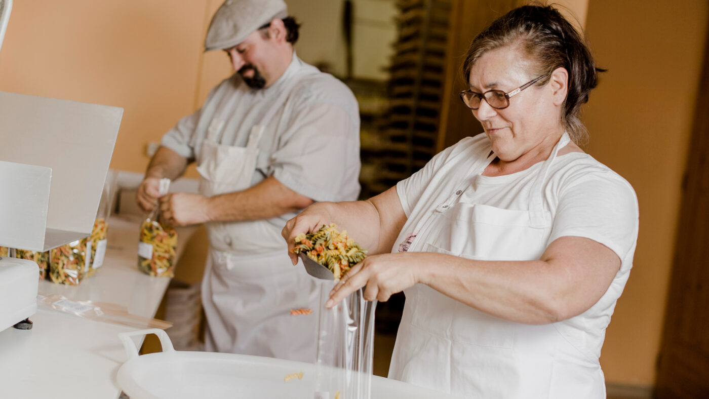 Zwei Personen in einer Küche beim Verarbeiten von Teigwaren.
