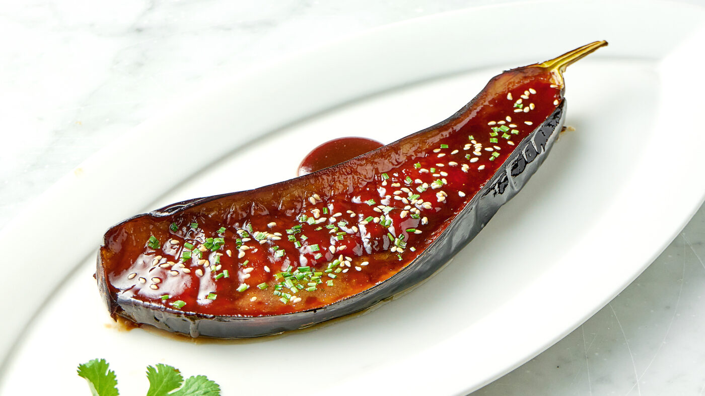 Eine mit Sauce zubereitete Melanzani auf einem Teller.
