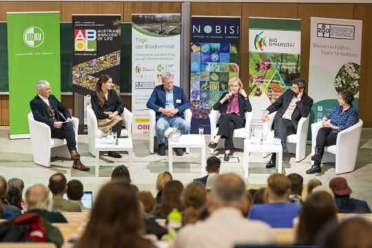 Mehrere Menschen sitzen auf einem Podium bei einer Diskussion.