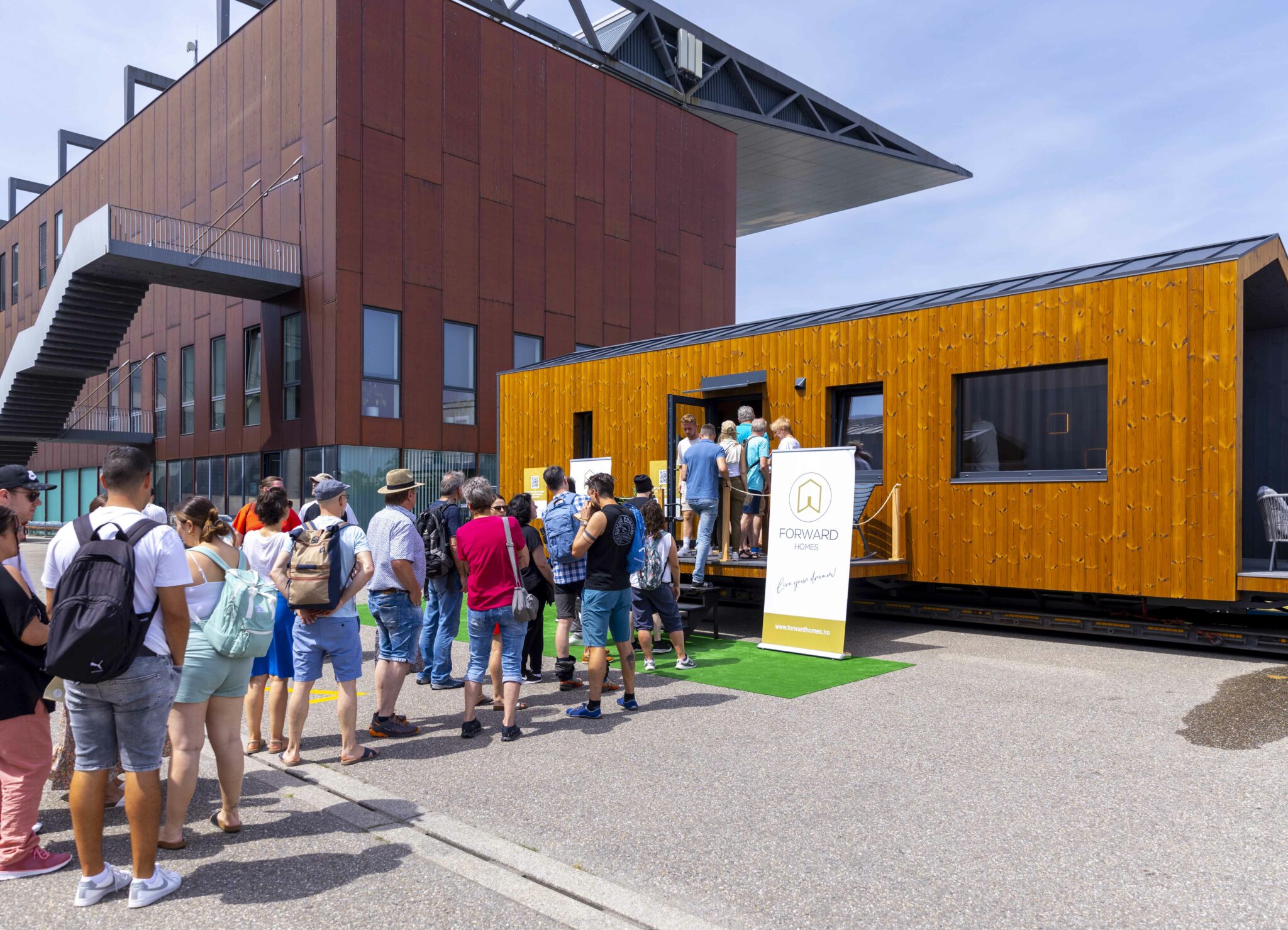 Mehrere Menschen stehen auf einer Messe vor einem kleinen Gebäude.