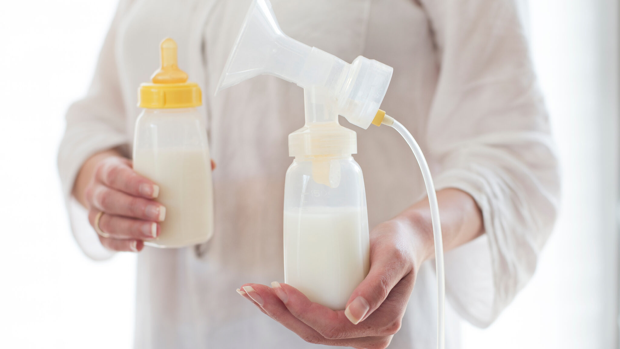 Eine Person in weißer Kleidung hält eine Pumpe und eine Flasche mit weißem Inhalt.