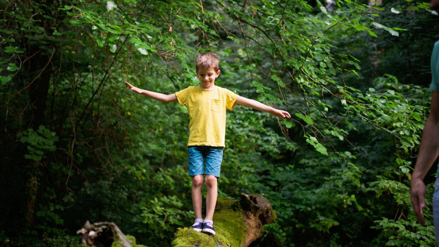 Ein Kind balanciert im Wald.