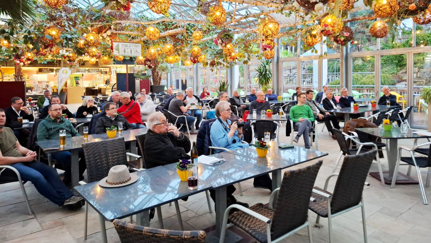 Mehrere Personen sitzen an einem Tisch unter einem Glasdach mit vielen bunten Lampignons.