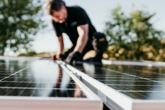 Eine Person verbaut PV-Zellen auf einer Fläche.