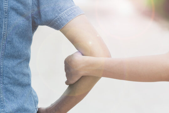 Eine Person hält eine andere am Arm.