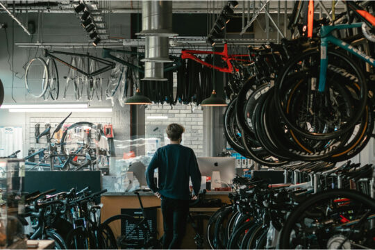 Ein Mann steht in einem Geschäft, in dem Fahrräder repariert werden.