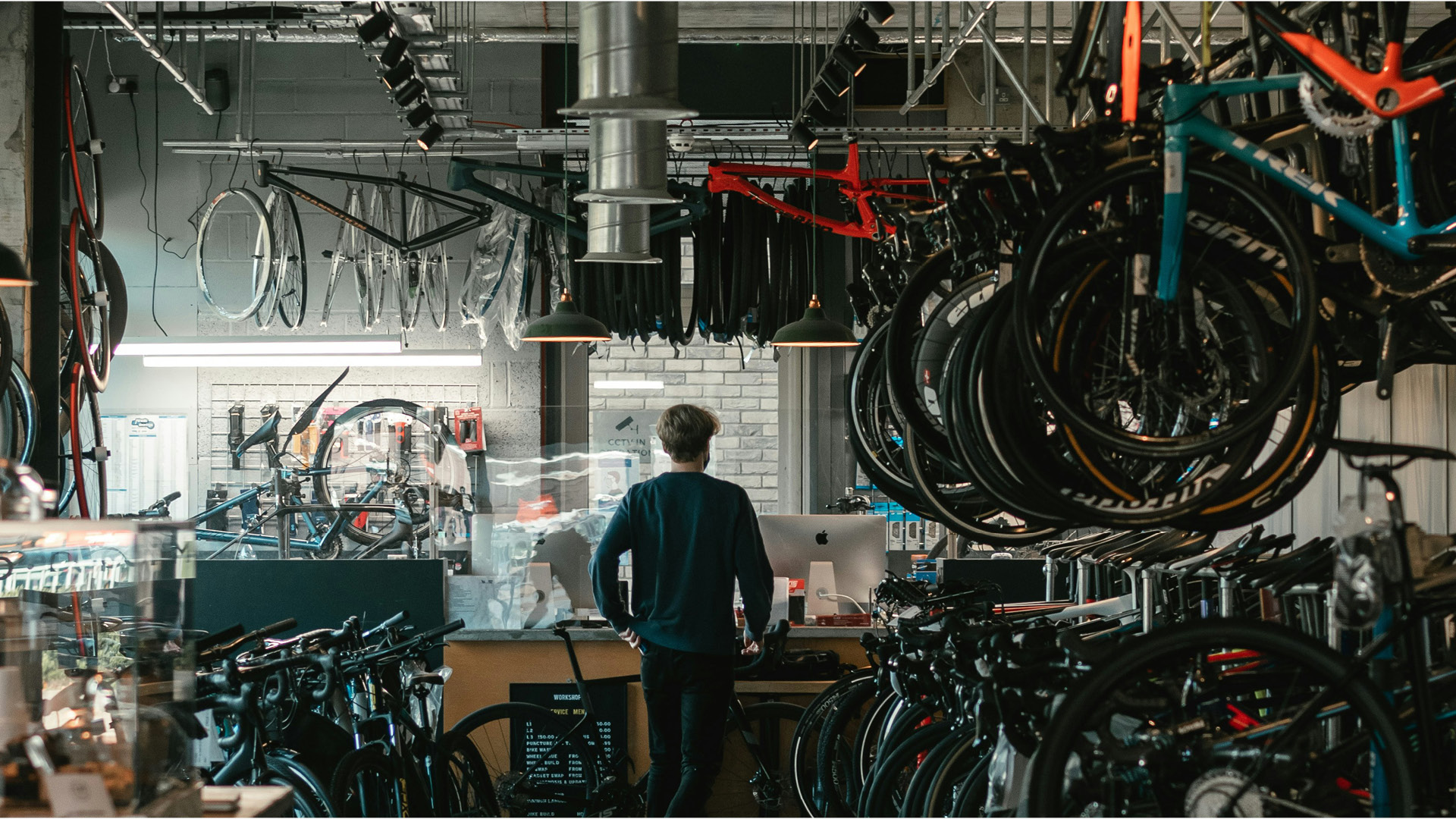 Ein Mann steht in einem Geschäft, in dem Fahrräder repariert werden.