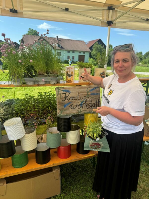 Eine Frau steht neben einem Schild mit der Aufschrift "Kreativwerkstatt“.